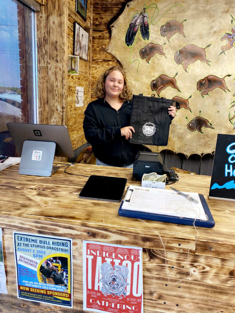 Phot of Julianna White Eagle standing behind counter at Sacred Storm Meats and Treats
